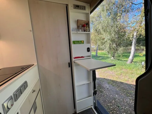 Regal neben der Schiebetür mit ausgeklapptem Tisch