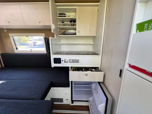 Küche mit geöffnetem Oberschrank, Besteckschublade und Kühlschrank