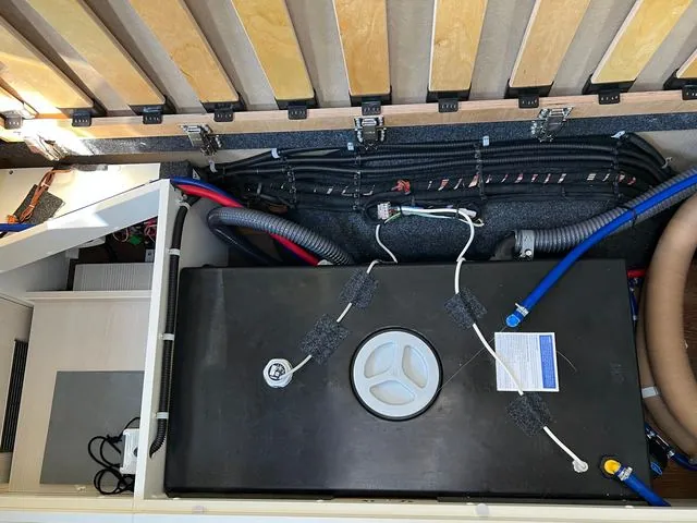 Schwarzer Frischwassertank unter der Sitzbank, daneben sauber verlegte Leitungen und Kabel